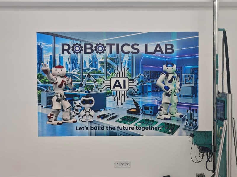 Полноцветное изображение ROBOTICS LAB с роботами на стене, рядом — настенный принтер
